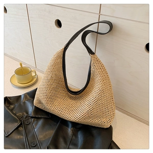 Detail of woven straw tote bag with black leather trim on a leather jacket background