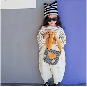 Détail du sac bandoulière enfant à motif pied-de-poule avec cœur en peluche jaune