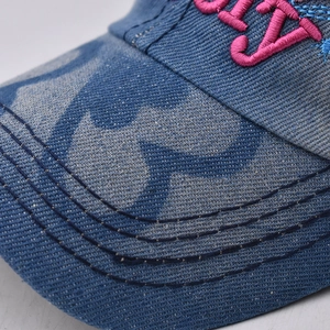 Close-up of blue washed denim baseball cap with premium pink 3D embroidered lettering