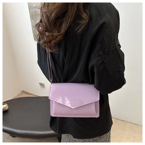 Detail of lavender patent leather crossbody bag with V-flap and gold logo lettering