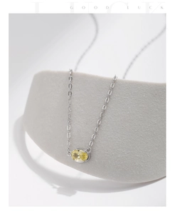 Detail of oval yellow zircon pendant with silver chain on textured stone pedestal