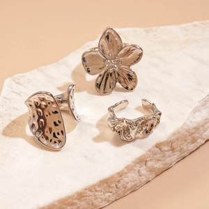 Detailed close-up of a three-piece silver ring set with floral and textured lava patterns