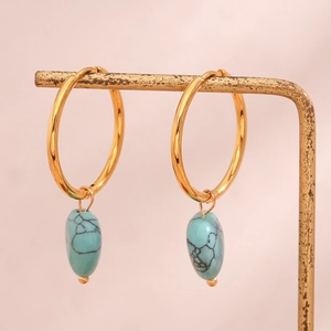 Detail of light blue stone heart pendant on gold hoop earrings for women