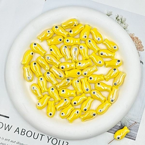 Macro shot of yellow fish-shaped ceramic beads for DIY jewelry making in a white bowl