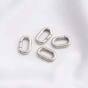 Detail von vier polierten silbernen Oval-Federverschlüssen für DIY-Schmuck auf weißem Stoff