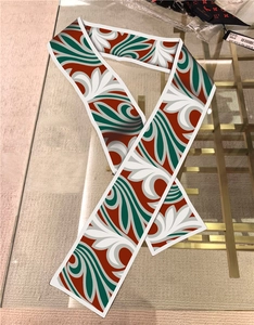 Close-up of oil painting style twilly silk scarf with red and green swirl pattern details