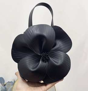 Close-up of black 3D flower petal tote bag with beaded center and leather texture