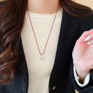 Detail of silver heart pendant with polished finish on a slim red cord necklace