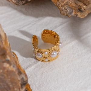 Detail of gold hammered texture ring featuring multiple inlaid pearls on a textured background