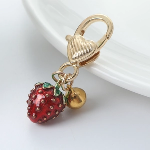 Creative strawberry keychain with gold bell and heart clasp on a white plate