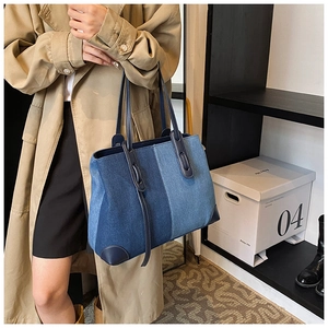 Detail view of large denim tote bag featuring blue patchwork design and leather handles