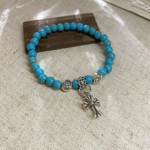 Gros plan d'un bracelet en perles de turquoise vintage avec un pendentif croix en argent