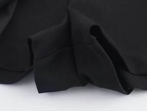 Détail du tissu plissé noir montrant la texture de qualité et les finitions de couture
