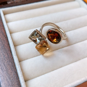 Detail of silver open ring featuring emerald-cut amber and square champagne zircon stones