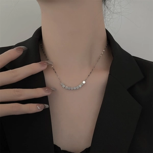 Detailopname van een zilveren ketting met vierkante hangers en geometrisch ontwerp