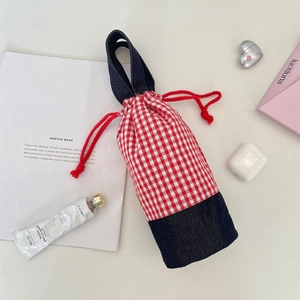 Detail of red checkered drawstring water bottle bag with denim base and handles