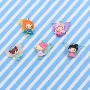 Macro view of five colorful resin fairy pendants with wings on striped fabric background