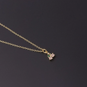 Detailed view of cherry fruit pendant with pink gemstones and gold chain on black background