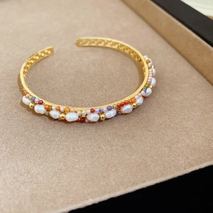 Vue détaillée du bracelet doré avec pierres colorées et perles dans un écrin en velours