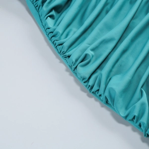 Detail of the turquoise pleated fabric with fine elastic smocked texture and stitching