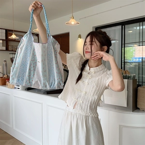 Close-up of small floral tote bag with blue stripes and drawstring, lifestyle shot