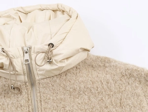 Détail du sweat beige en sherpa avec tissu nylon contrasté et fermeture éclair argentée