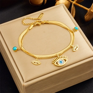 Macro view of gold stainless steel evil eye charms and blue beads on a layered chain