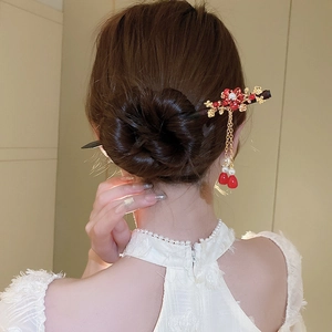Detail of flower hair stick with gold tassels and pearls worn on a hair bun