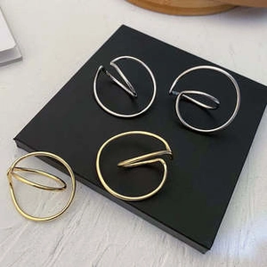 Close-up of stylish round hollow earrings in gold and silver finish on a black display stand