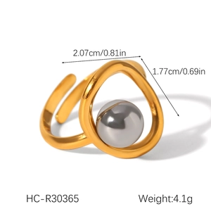 Macro detail of gold-plated twisted steel ring with a grey sphere and product dimensions