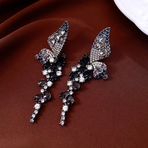 Macro shot of butterfly tassel earrings with blue crystals on brown velvet