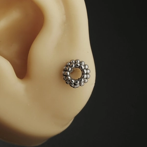 16G stainless steel skull barbell earring shown on ear model with textured bead circular design