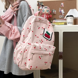 Mochila de pana rosa con estampado de cerezas y bordado en un entorno acogedor