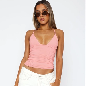 Close-up of pink v-neck camisole top with thin straps on a model with white trousers