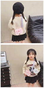 Sac bandoulière enfant en silicone rose avec nœud et sangle arc-en-ciel sur modèle