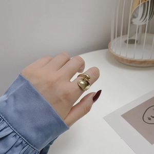 Close-up of a wide gold-plated open ring with an irregular curved surface on finger
