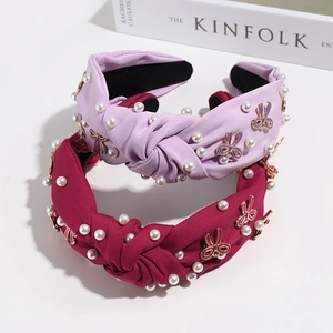 Detail of vintage knotted headbands with white pearls and gold rabbit charms on fabric