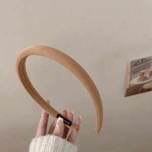 Détail d'un serre-tête épais camel fait main avec texture rayée et étiquette tissée