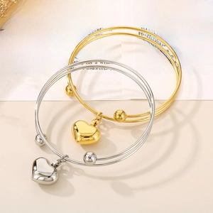 Close-up of triple-layered heart bangle in gold and silver on vintage newspaper