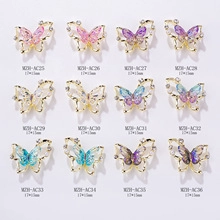 Macro view of butterfly alloy nail charms with gold borders and assorted rhinestones