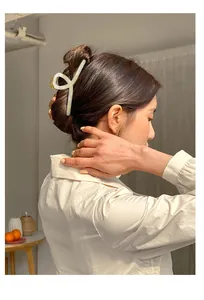 Close-up of a large cream marble hair claw clip worn by a model in soft natural light