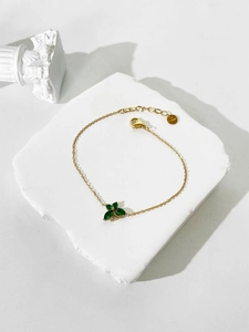 Detail of 18K gold stainless steel bracelet with green zircon butterfly charm on stone