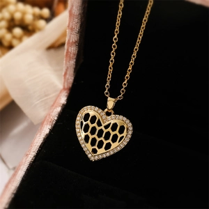 Detailed close-up of a gold heart pendant with honeycomb cutout and white zircon micro-paving