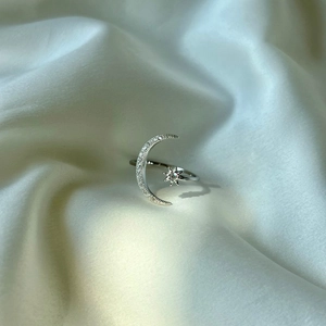 Detailed view of S925 sterling silver moon and star ring on white silk background