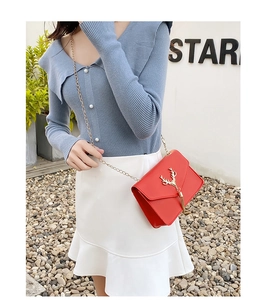 Detail of red leather crossbody bag featuring gold deer head decor and metal tassels