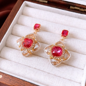 Dettaglio di orecchini vintage a rombo con gemme rosse e finiture in oro
