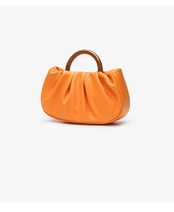 Detail of orange pleated cloud handbag featuring a round resin brown top handle