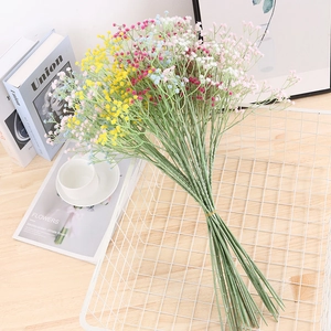 Colorful artificial gypsophila bouquet in a white iron basket on a wooden table
