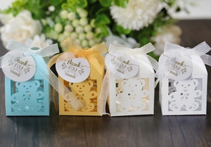 Detail of laser-cut bear candy boxes with ribbons and thank you tags in four colors