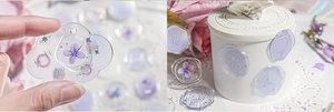Close-up of translucent lavender wax seal stickers with gold foil and dried flowers